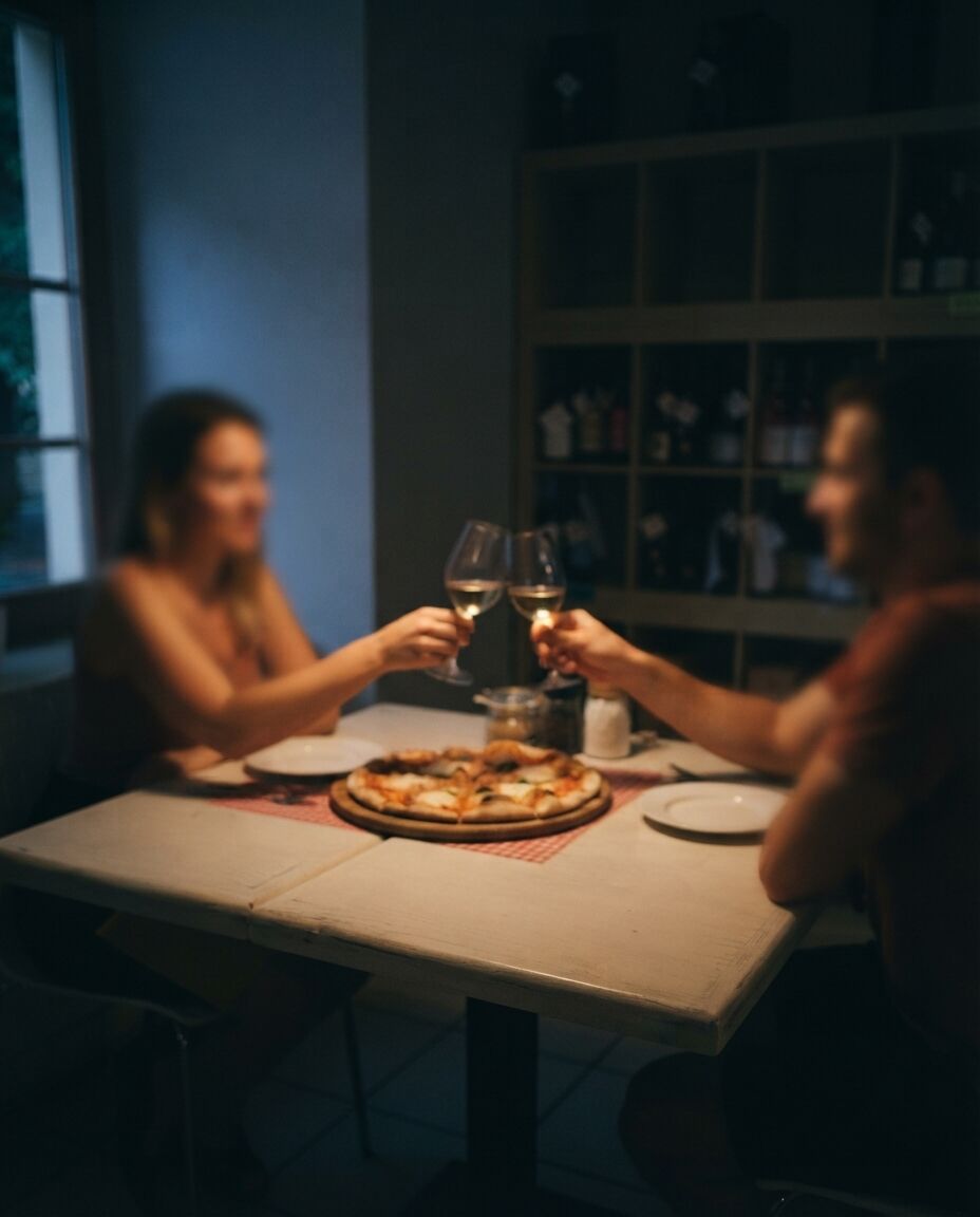 Dvojice si připíjí u stolu s pizzou